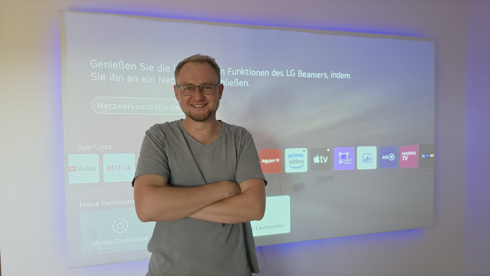 Manuel Mathwig mit verschränkten Armen vor einer Projektion in einem Wohnraum